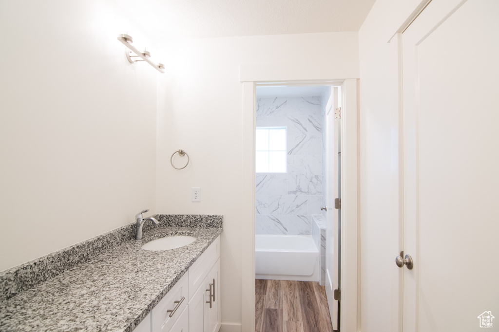 Bathroom with tiled shower / bath, vanity, and hardwood / wood-style floors