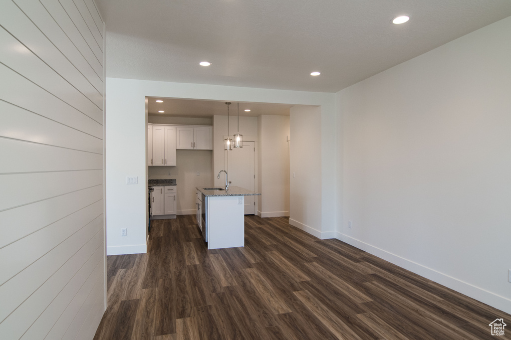 Unfurnished living room with sink, a notable chandelier, and dark wood-type flooring