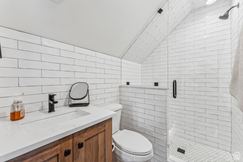 Bathroom featuring tile walls, walk in shower, vanity, and toilet