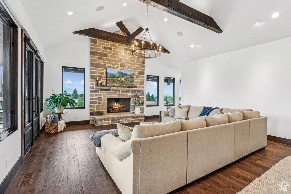 Living room featuring beamed ceiling, dark hardwood / wood-style floors, a chandelier, and a fireplace