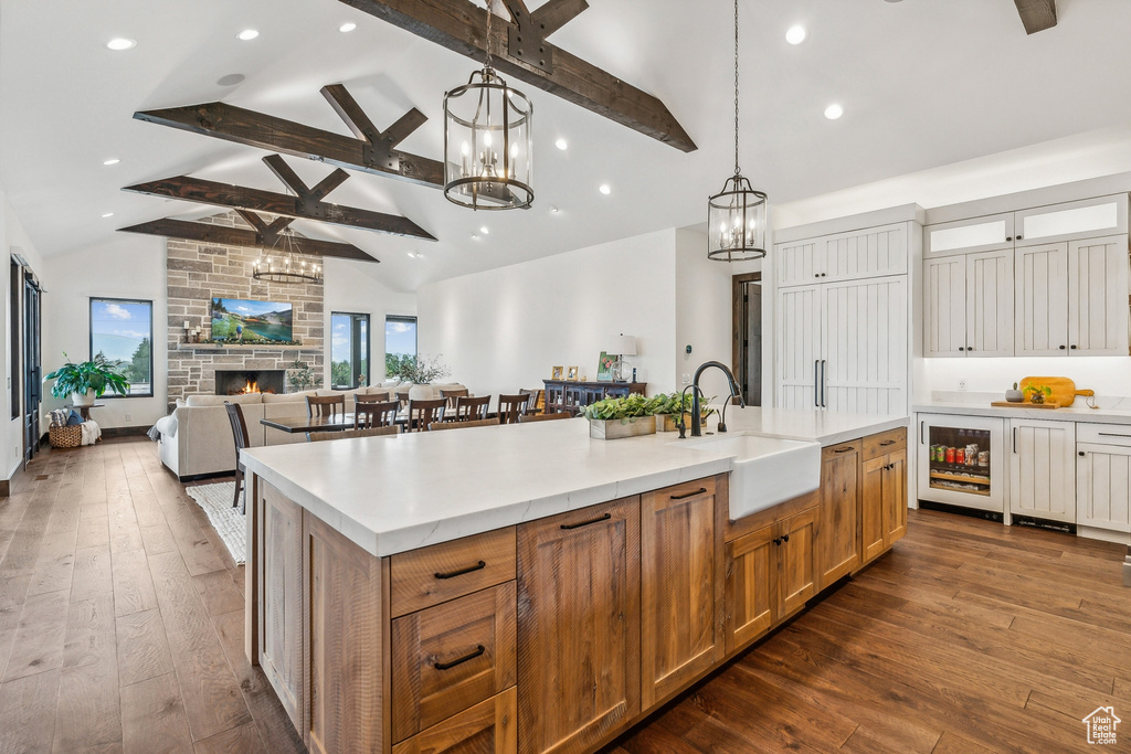 Kitchen with a center island with sink, sink, dark hardwood / wood-style flooring, and beverage cooler