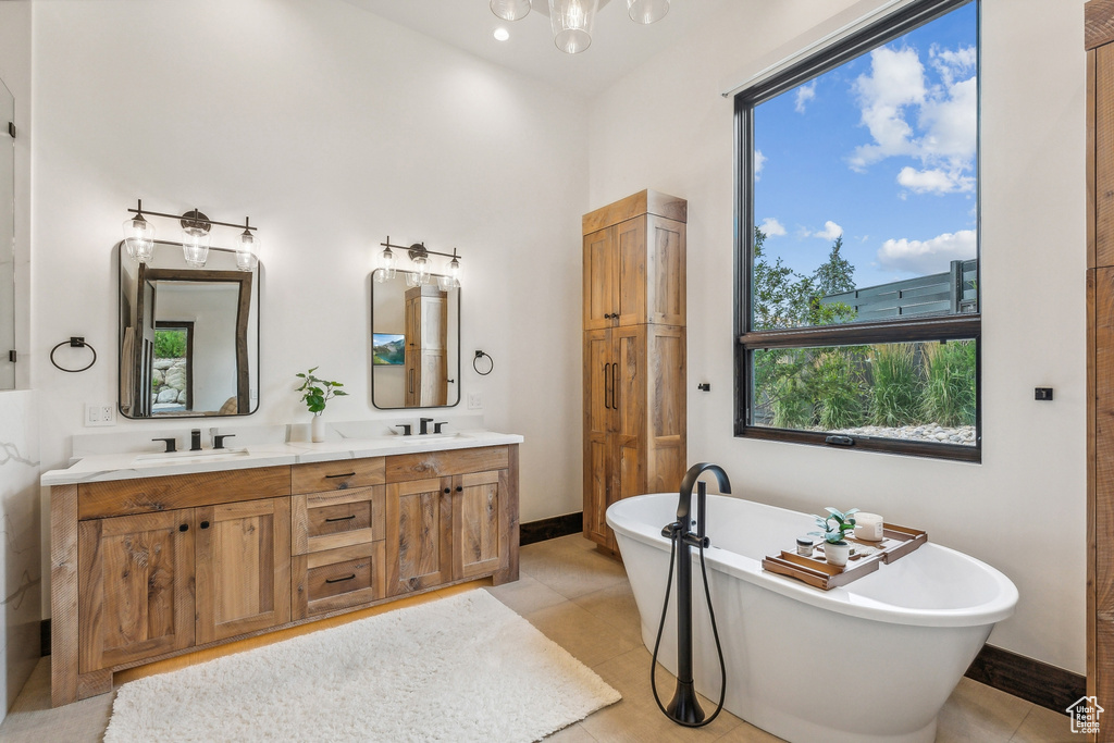 Bathroom with tile patterned floors, dual bowl vanity, and a tub to relax in