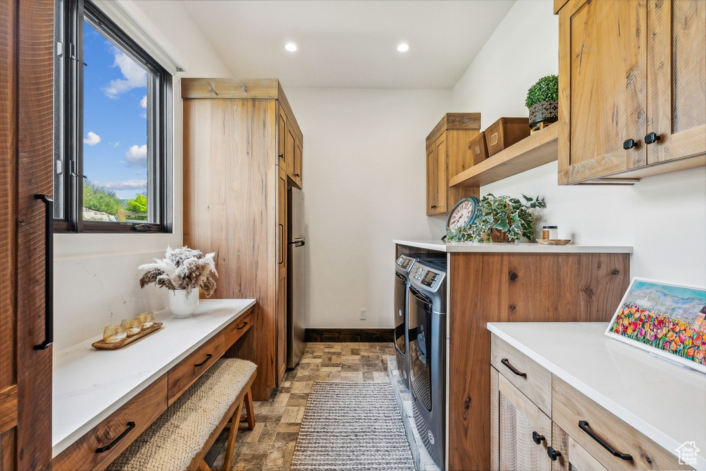 Clothes washing area featuring washing machine and clothes dryer, light tile patterned flooring, and cabinets