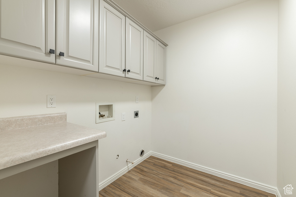 Washroom featuring hookup for an electric dryer, cabinets, wood-type flooring, gas dryer hookup, and washer hookup