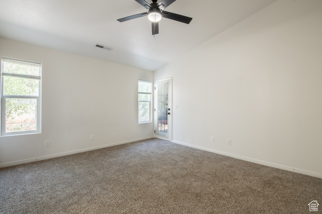 Carpeted spare room with ceiling fan and lofted ceiling