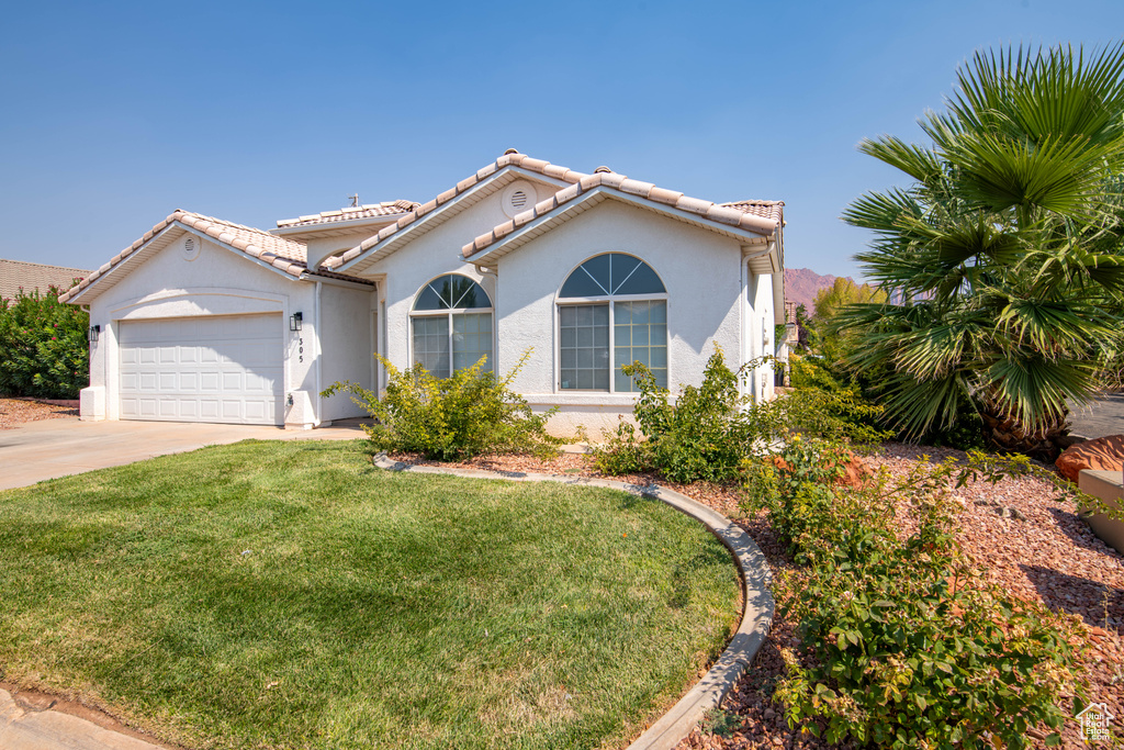 Mediterranean / spanish house featuring a garage and a front yard