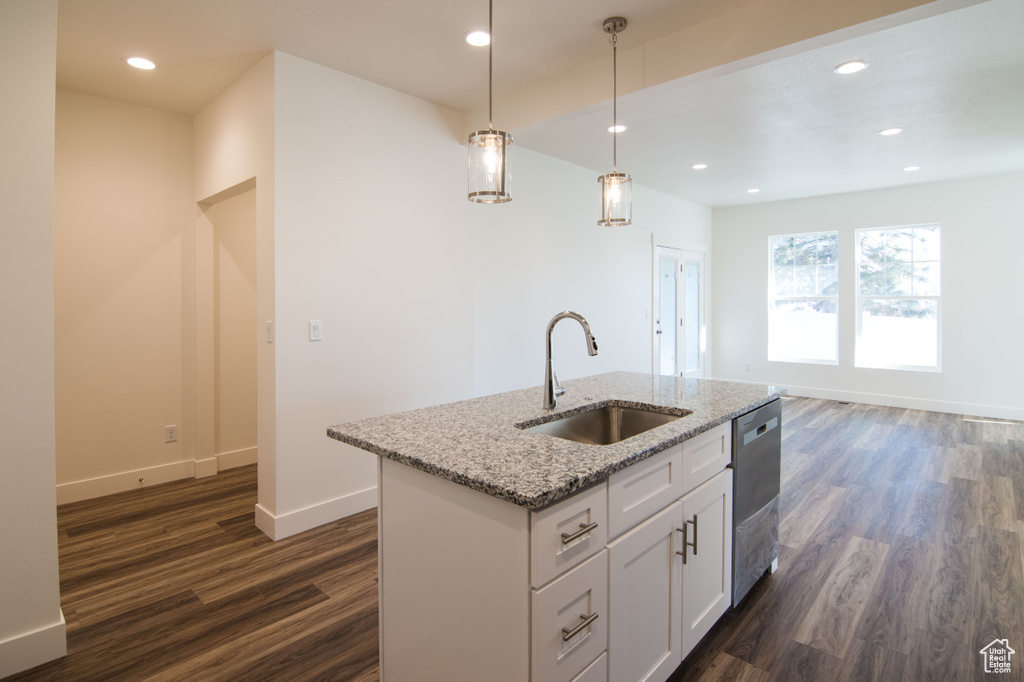 Kitchen featuring dark hardwood / wood-style floors, white cabinetry, light stone countertops, a center island with sink, and sink