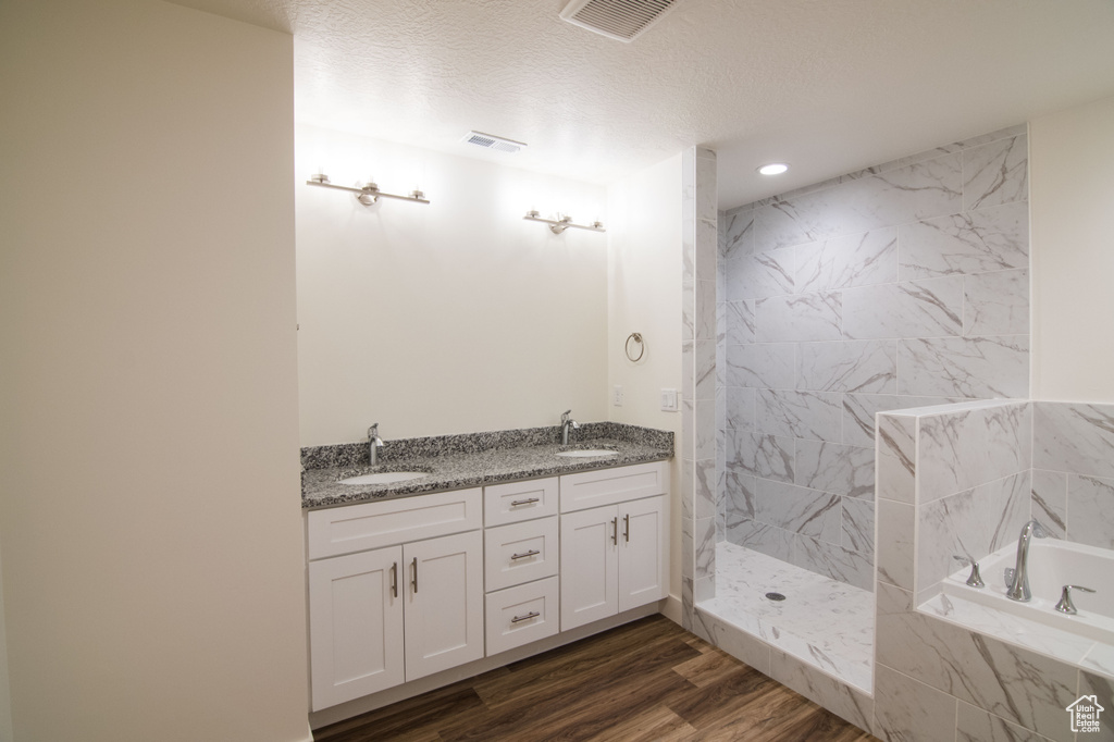 Bathroom with a textured ceiling, double sink vanity, hardwood / wood-style floors, and independent shower and bath