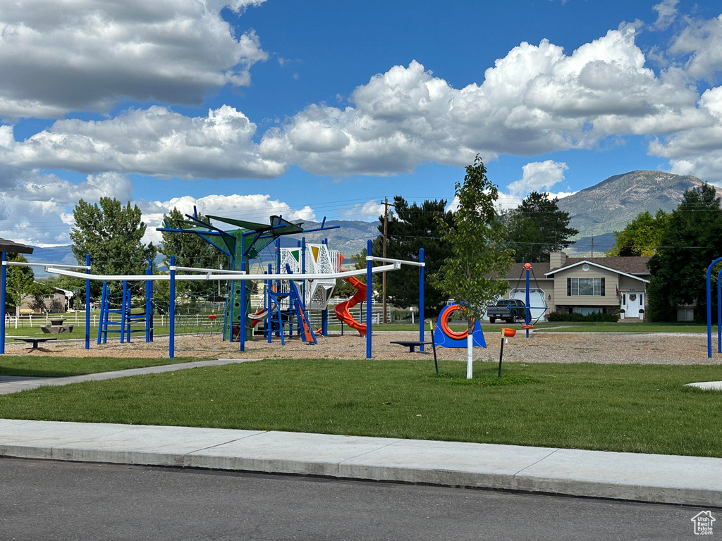 View of playground featuring a lawn and a mountain view