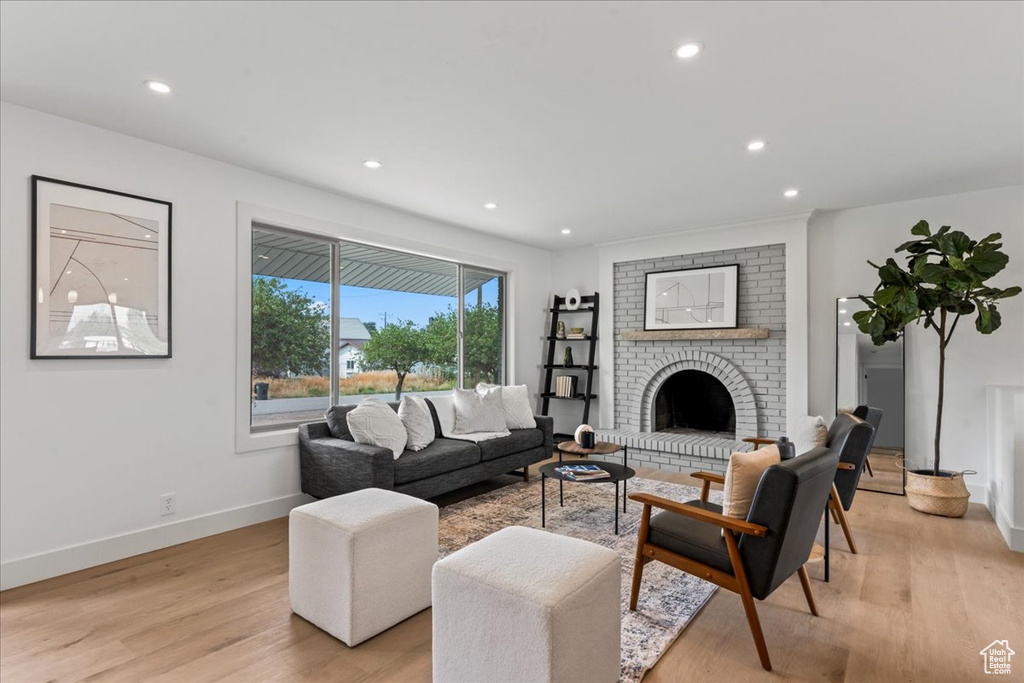 Living room featuring light hardwood / wood-style flooring, a fireplace, and brick wall