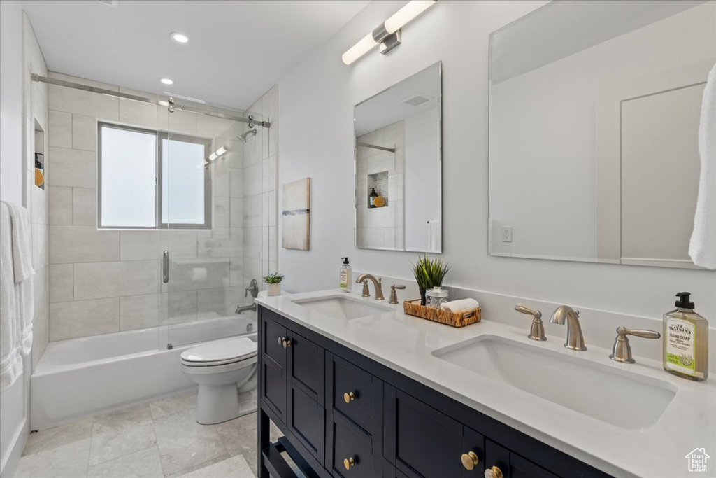 Full bathroom with dual vanity, tiled shower / bath, toilet, and tile patterned flooring