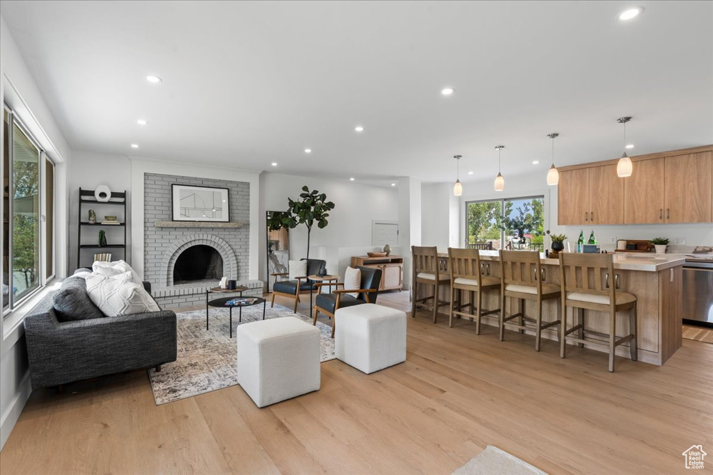 Living room featuring a brick fireplace, light hardwood / wood-style flooring, and brick wall