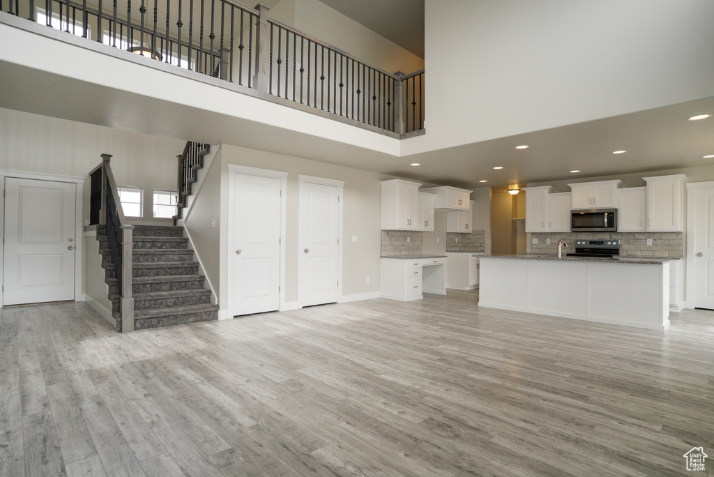 Unfurnished living room featuring light hardwood / wood-style flooring and a high ceiling