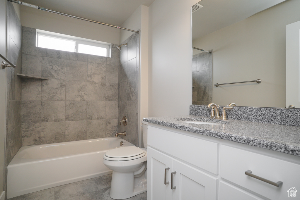 Full bathroom with vanity, tiled shower / bath combo, toilet, and tile patterned flooring