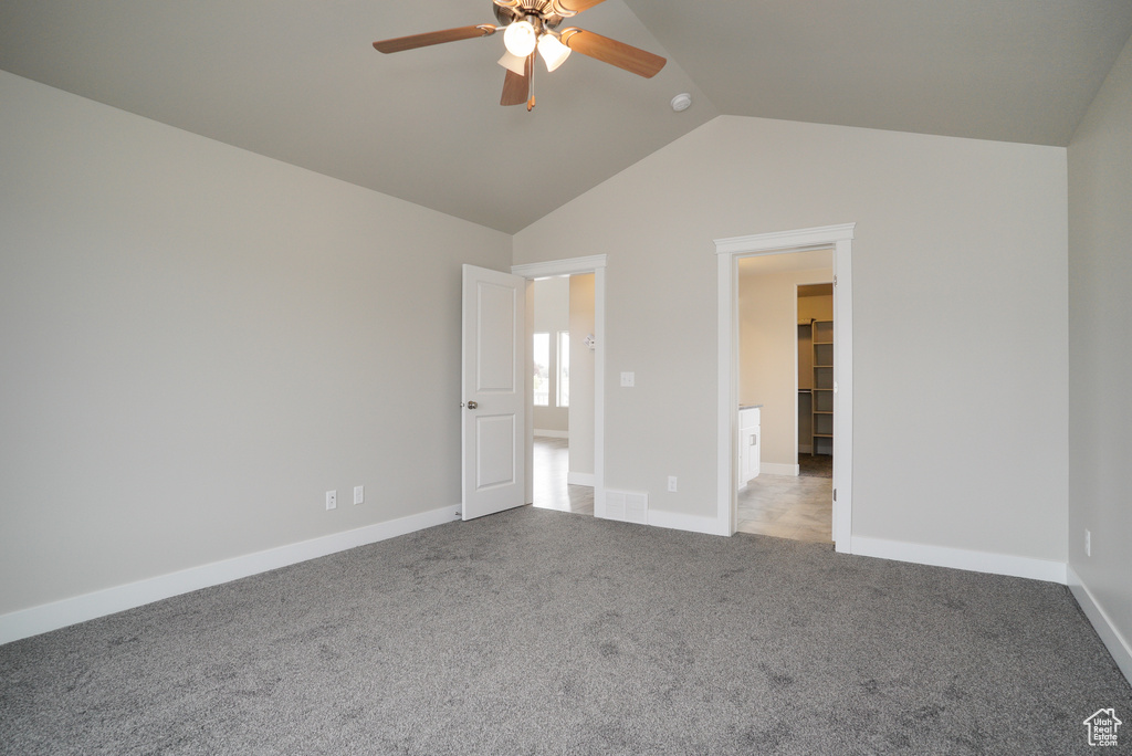 Unfurnished bedroom featuring ceiling fan, lofted ceiling, a spacious closet, a closet, and light colored carpet