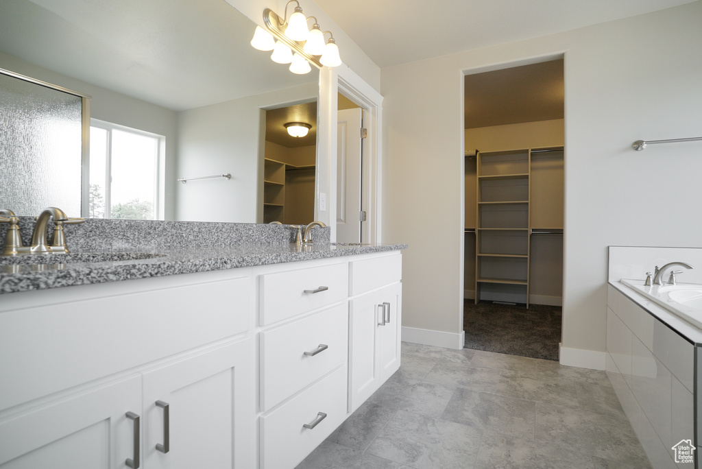 Bathroom featuring double vanity, a relaxing tiled tub, and tile patterned flooring