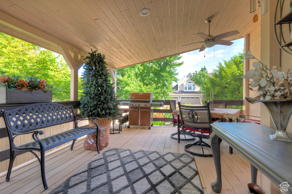 Exterior space featuring a wooden deck, grilling area, and ceiling fan