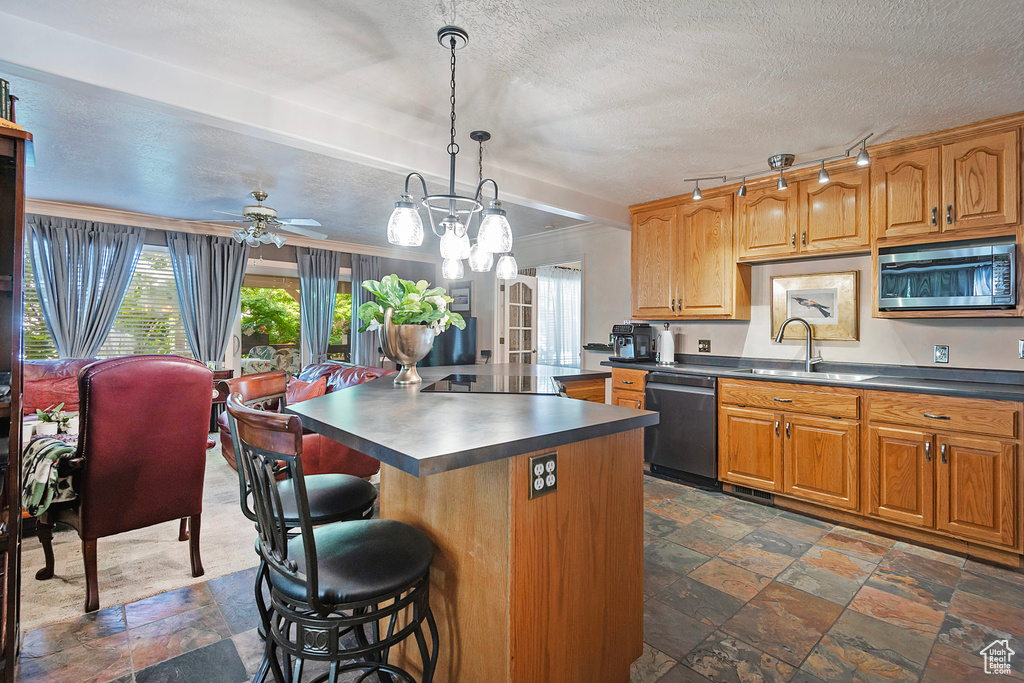 Kitchen featuring sink, black appliances, dark tile patterned flooring, and a center island