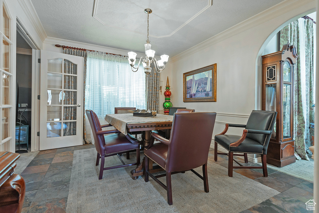 Dining space with ornamental molding, tile patterned flooring, a notable chandelier, and a healthy amount of sunlight