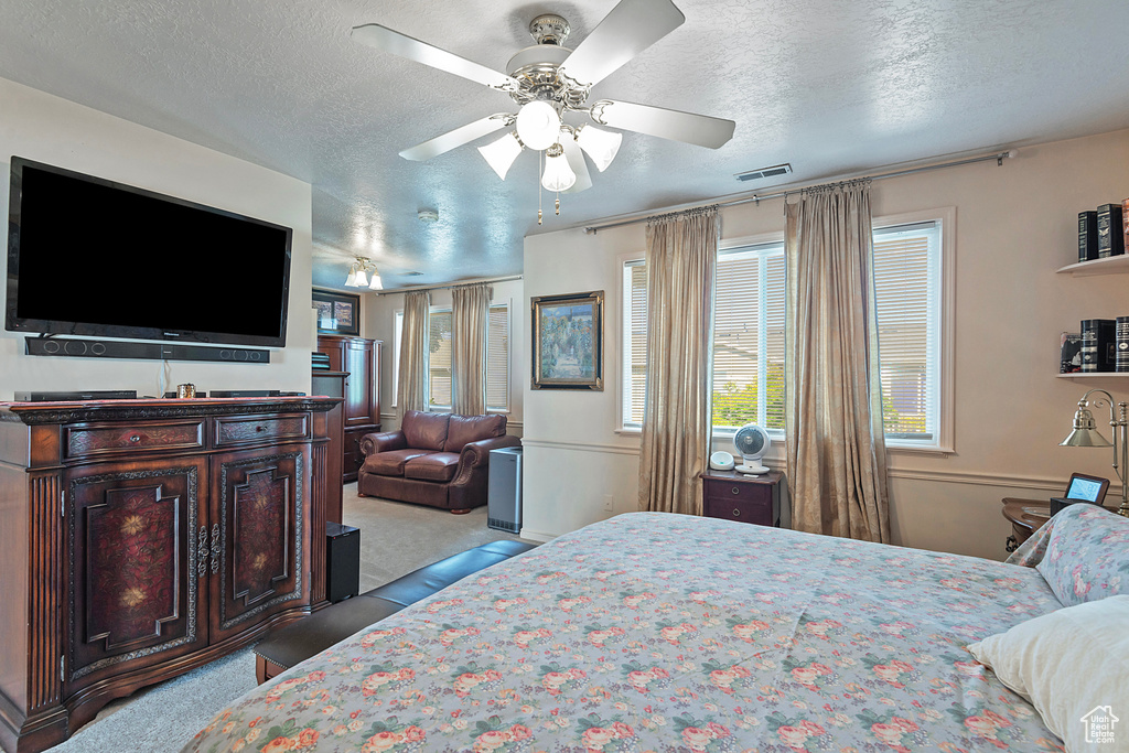 Carpeted bedroom with a textured ceiling and ceiling fan