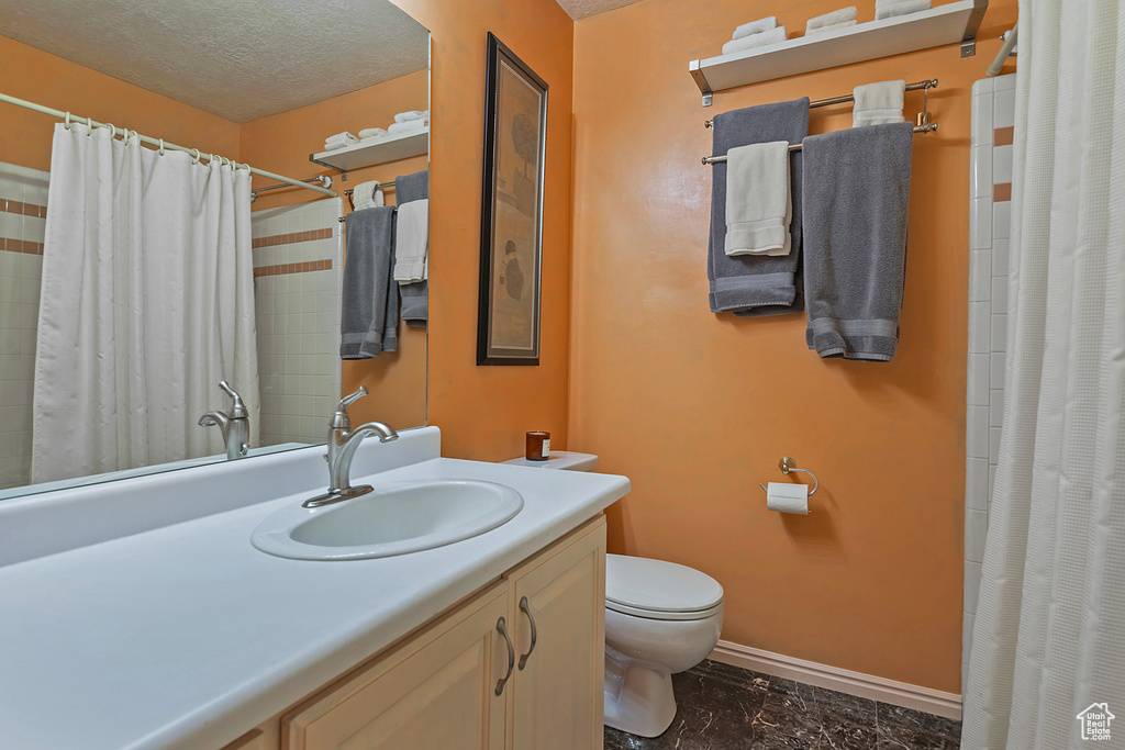 Bathroom with vanity, tile patterned floors, a textured ceiling, and toilet