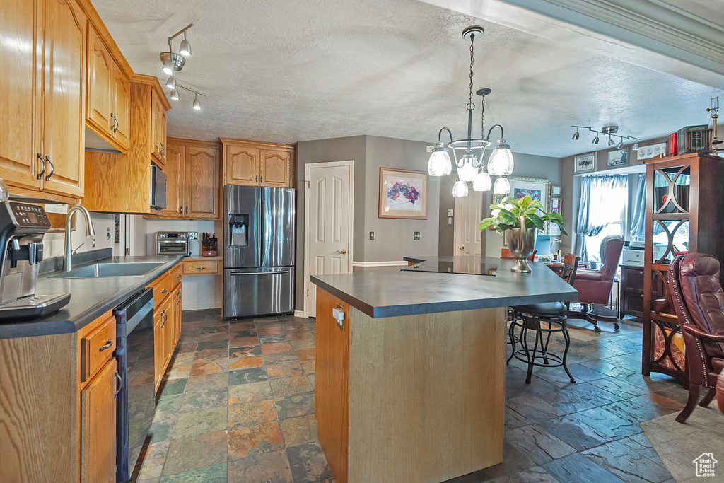 Kitchen featuring appliances with stainless steel finishes, dark tile patterned floors, sink, rail lighting, and a center island