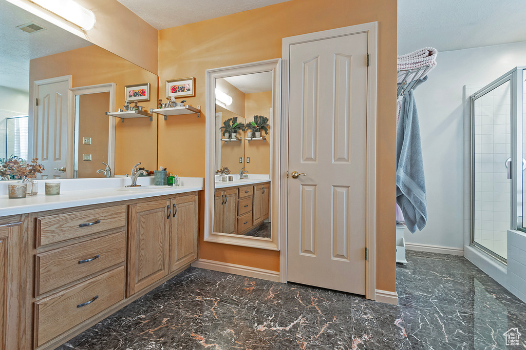 Bathroom with a shower with shower door, tile patterned floors, and vanity