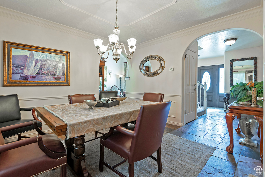 Dining space featuring ornamental molding, a notable chandelier, and tile patterned floors