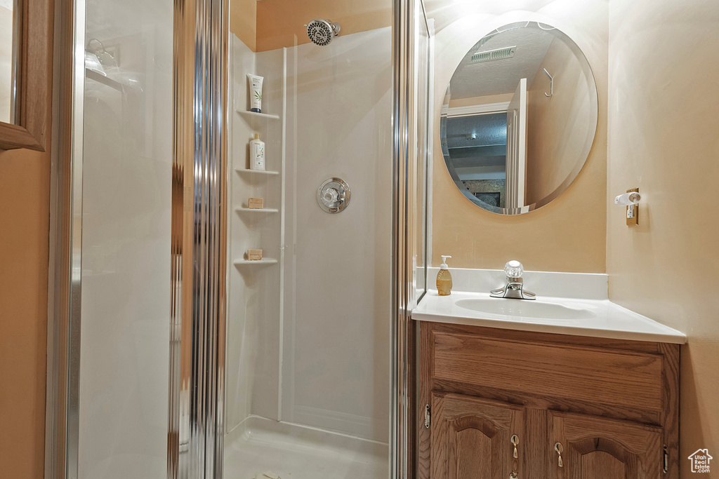 Bathroom featuring a shower with shower door and vanity