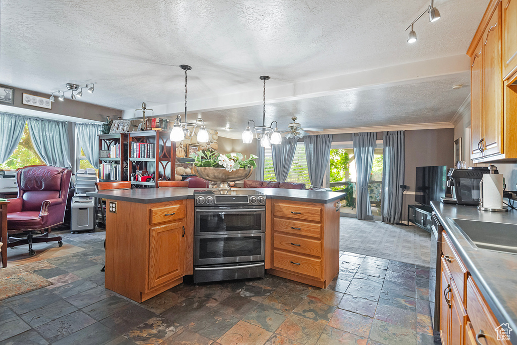 Kitchen with range with two ovens, dark tile patterned flooring, a textured ceiling, a center island, and ornamental molding