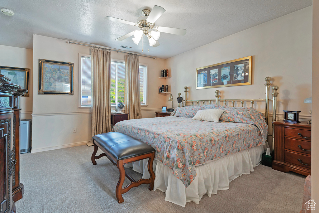 Bedroom featuring a textured ceiling, light colored carpet, and ceiling fan