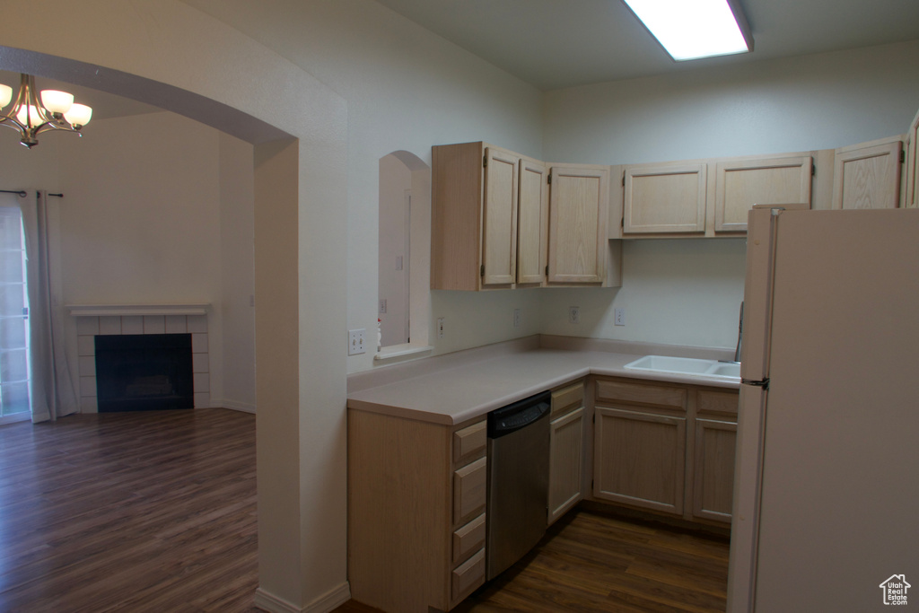 Kitchen featuring white refrigerator, dark hardwood / wood-style floors, a tiled fireplace, and dishwasher