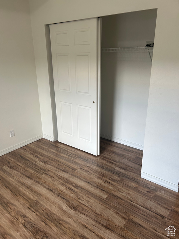 Unfurnished bedroom with dark wood-type flooring and a closet