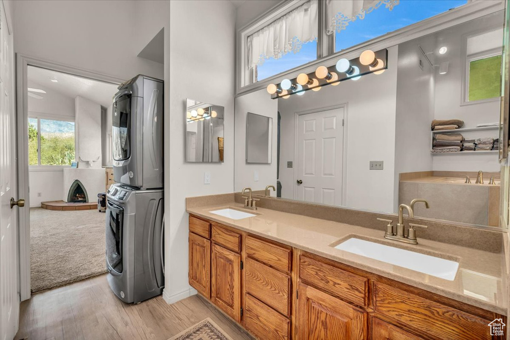 Bathroom featuring stacked washer / dryer, double sink vanity, and hardwood / wood-style floors