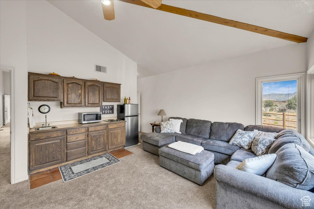 Carpeted living room featuring beam ceiling, high vaulted ceiling, sink, and ceiling fan