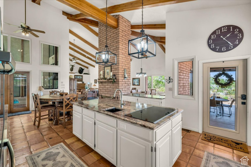 Kitchen with white cabinets, light tile patterned floors, decorative light fixtures, beamed ceiling, and sink