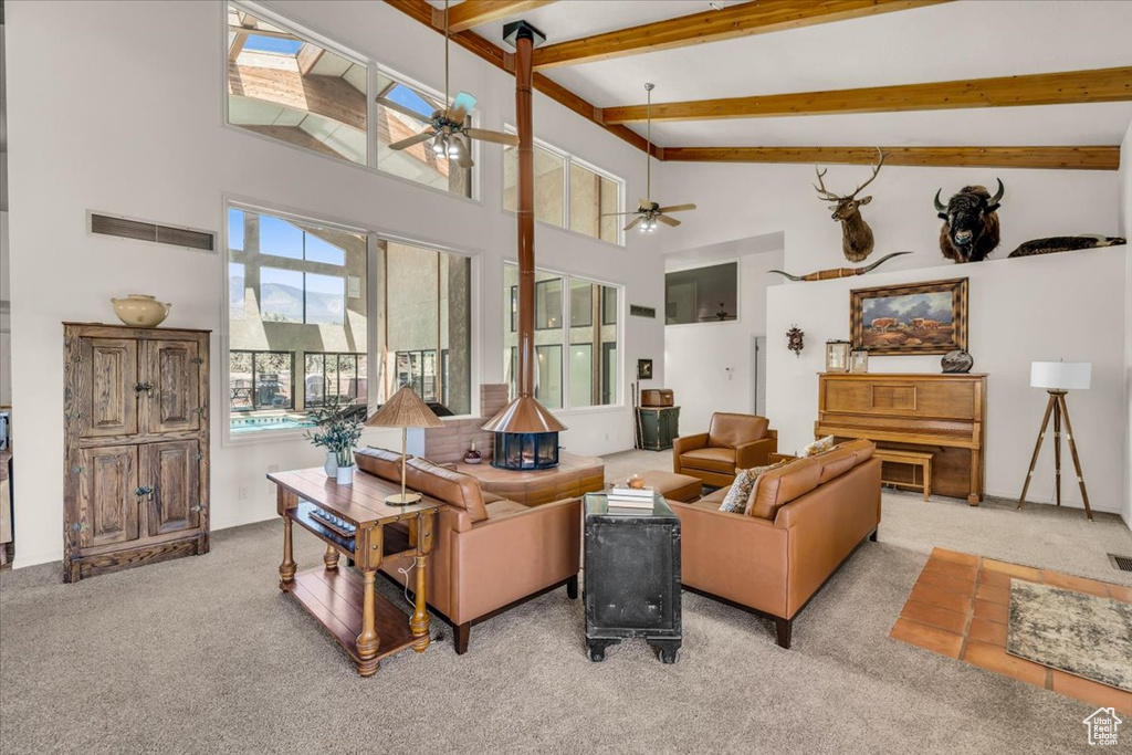 Living room with beamed ceiling, ceiling fan, high vaulted ceiling, and light colored carpet