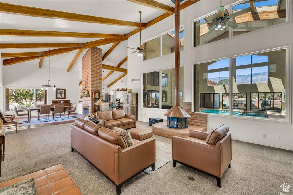 Carpeted living room featuring beamed ceiling, ceiling fan, and high vaulted ceiling
