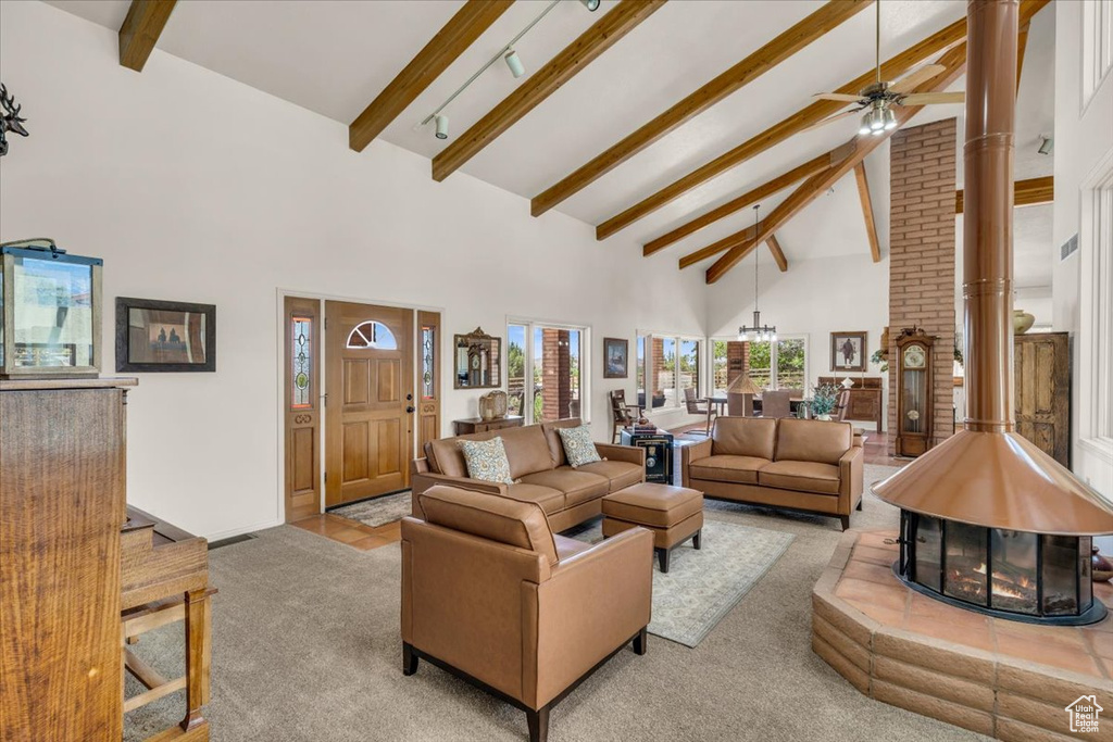 Living room with light carpet, ceiling fan, a fireplace, beamed ceiling, and brick wall
