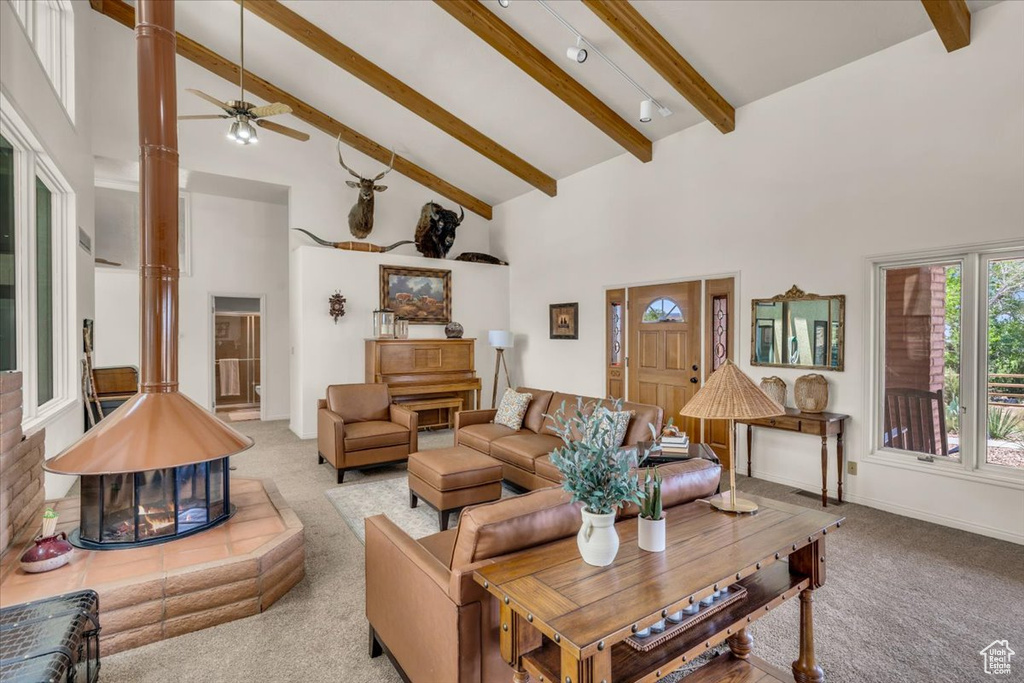 Carpeted living room with ceiling fan, high vaulted ceiling, beamed ceiling, and a multi sided fireplace