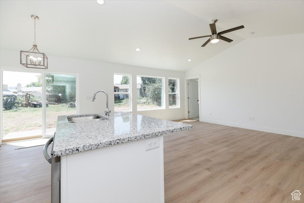 Kitchen with pendant lighting, vaulted ceiling, and light hardwood / wood-style floors