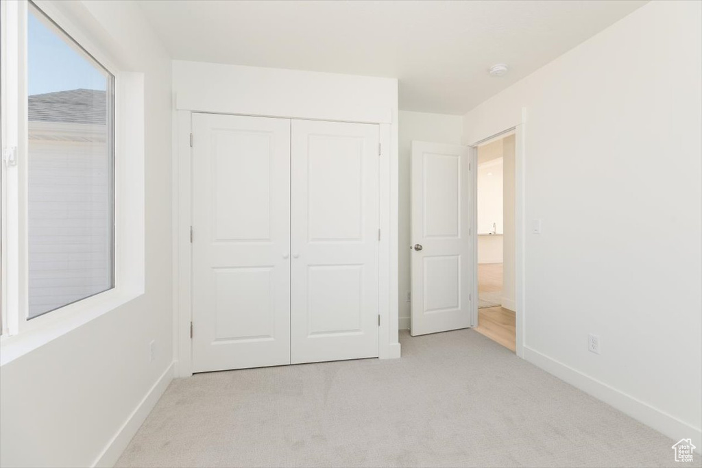 Unfurnished bedroom with light colored carpet and a closet