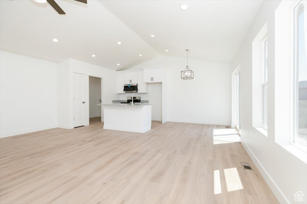 Unfurnished living room with lofted ceiling, light hardwood / wood-style flooring, ceiling fan, and sink