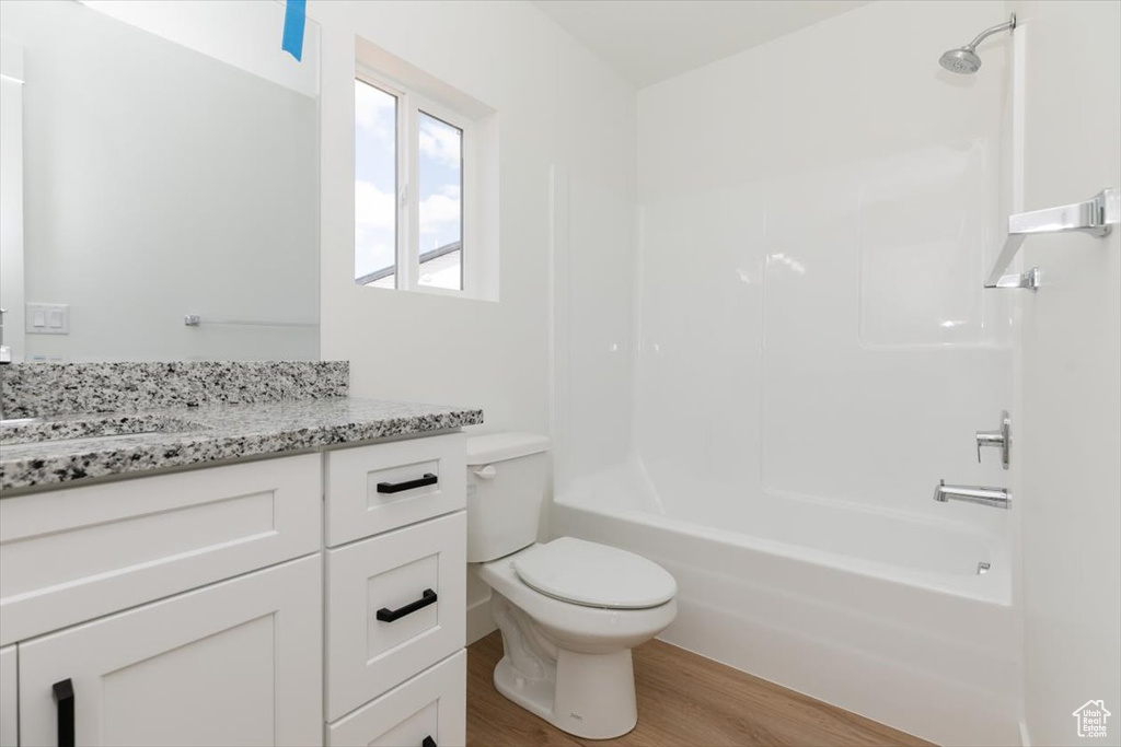 Full bathroom with hardwood / wood-style floors, toilet, bathtub / shower combination, and vanity