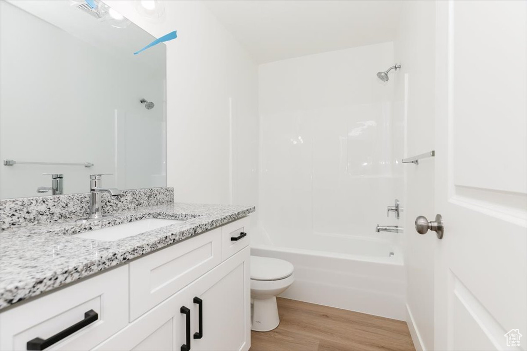 Full bathroom featuring toilet, hardwood / wood-style flooring, tub / shower combination, and vanity