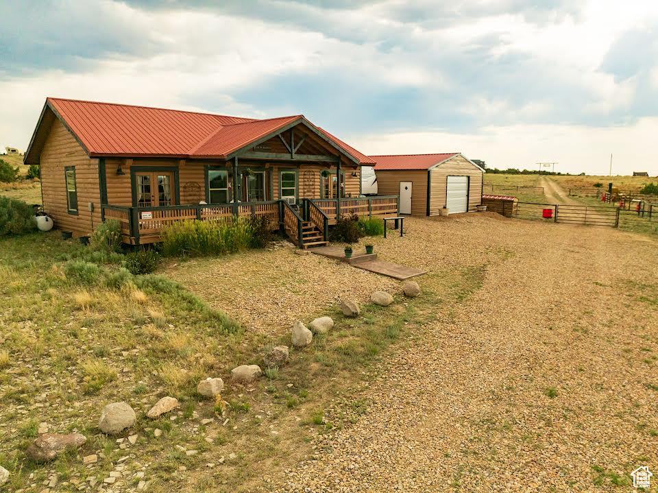 View of front of home featuring a garage, an outbuilding, and a wooden deck