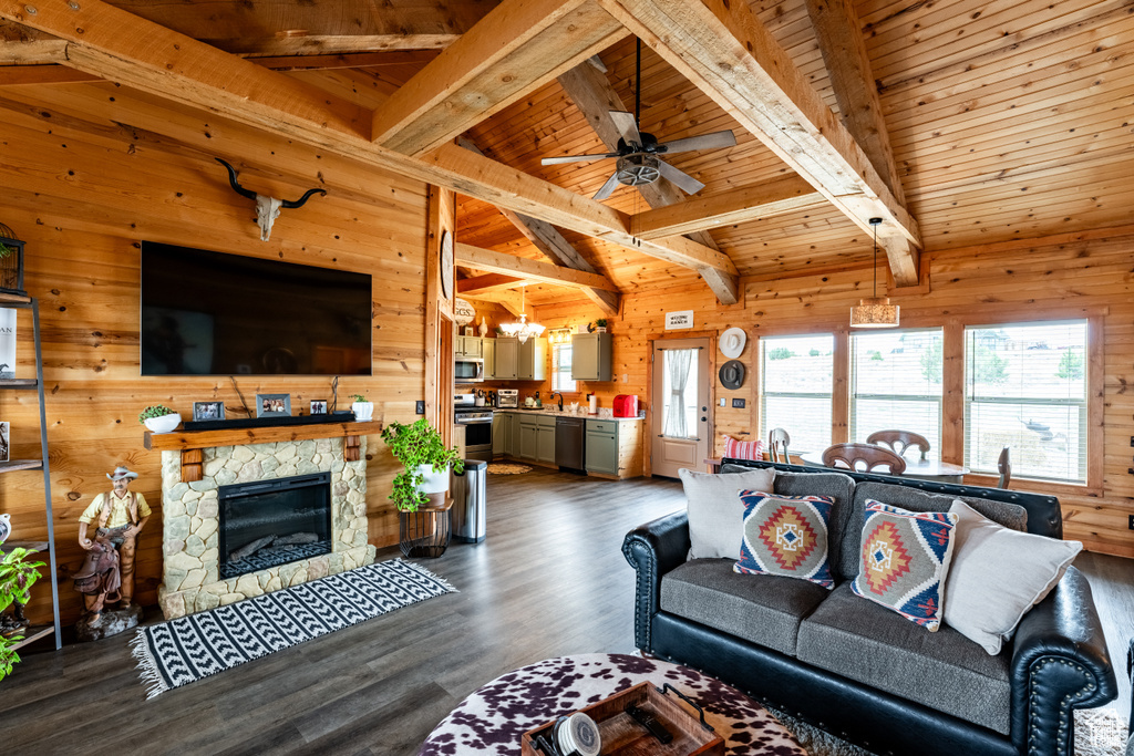 Living room featuring a stone fireplace, dark wood-type flooring, wooden walls, and wooden ceiling