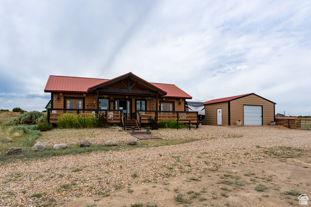 Log home featuring a garage, covered porch, and an outdoor structure