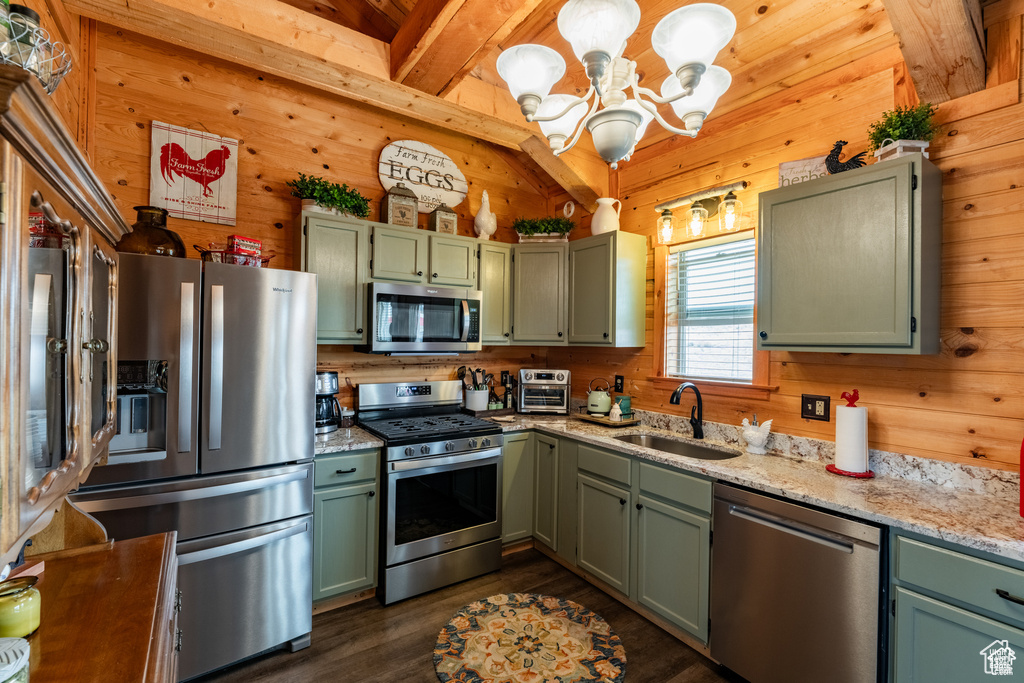 Kitchen with dark wood-type flooring, wood walls, stainless steel appliances, and sink