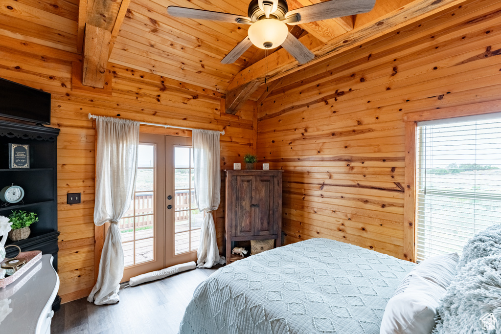 Bedroom featuring wooden walls, vaulted ceiling with beams, ceiling fan, wood-type flooring, and access to exterior